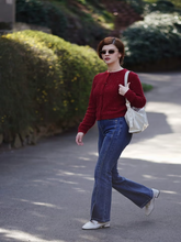 A lady wears red cardigan and jeans